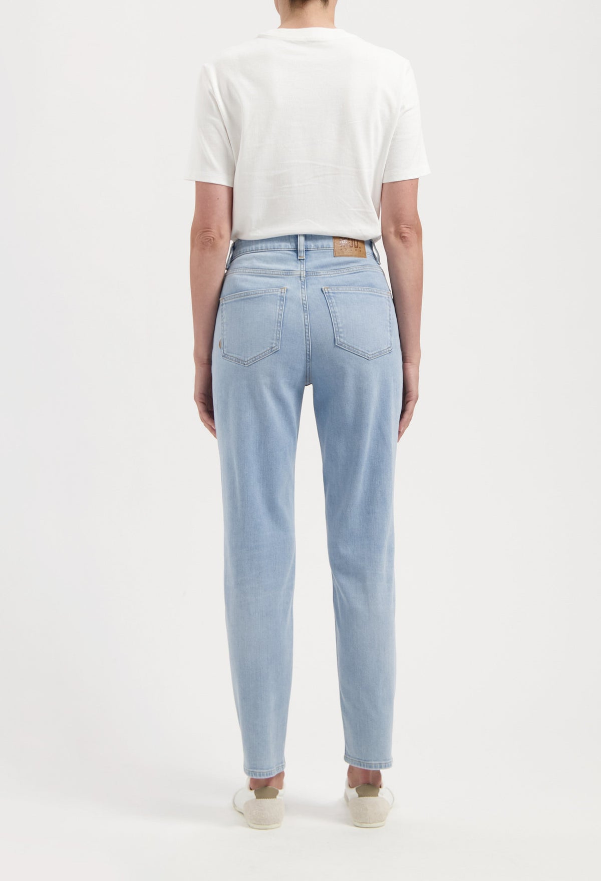 Back view of a person wearing light blue, straight-leg jeans paired with a white short-sleeve top, showcasing casual style.