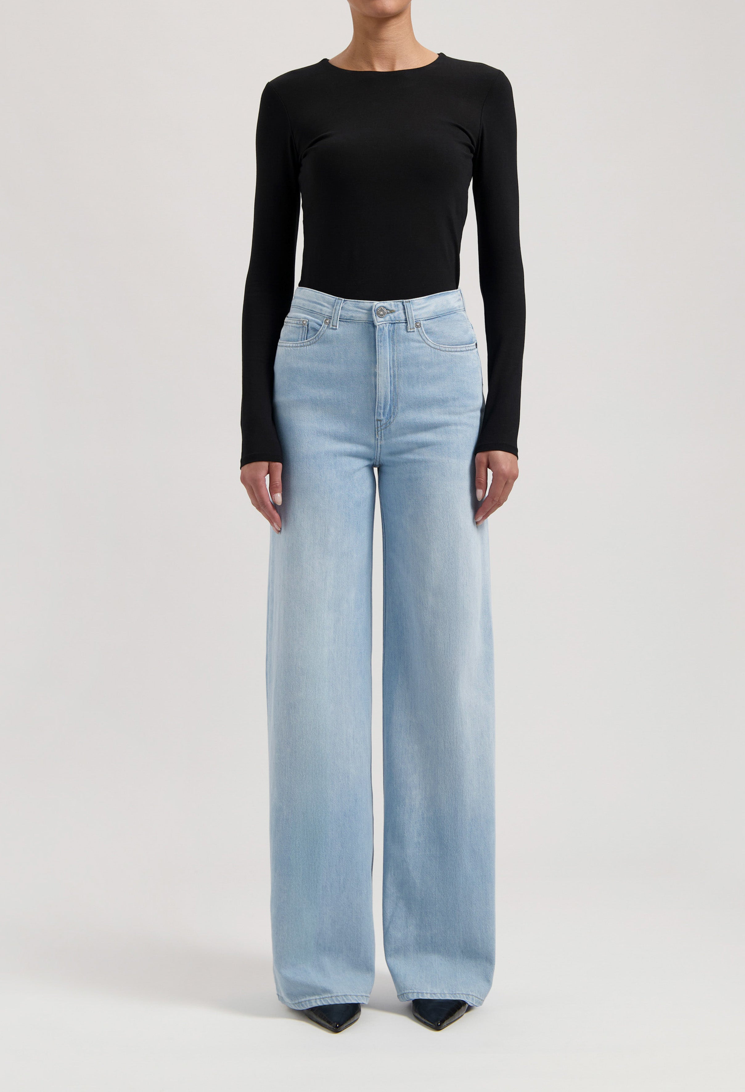 Wide-leg light blue denim jeans paired with a black, long-sleeve fitted top, showcasing casual chic fashion style.