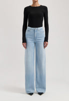 Wide-leg light blue denim jeans paired with a black, long-sleeve fitted top, showcasing casual chic fashion style.