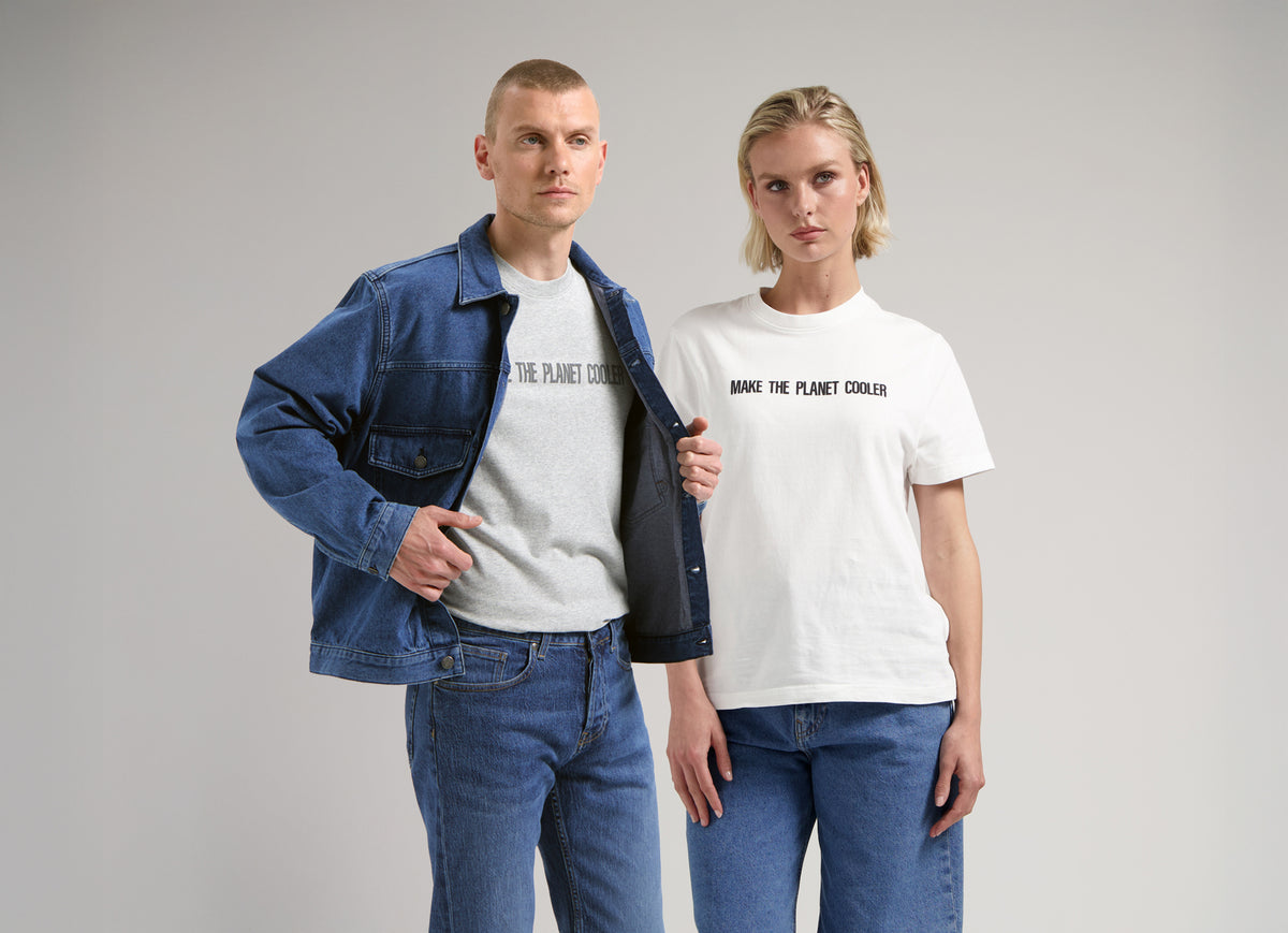 Sustainable MUD Jeans in classic blue denim with utility pockets, paired with a matching blue jacket and white sneakers.
