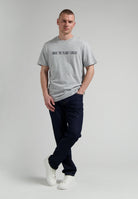 Sustainable MUD Jeans in classic blue denim, crafted from ethical materials, paired with a simple black tee and white sneakers.