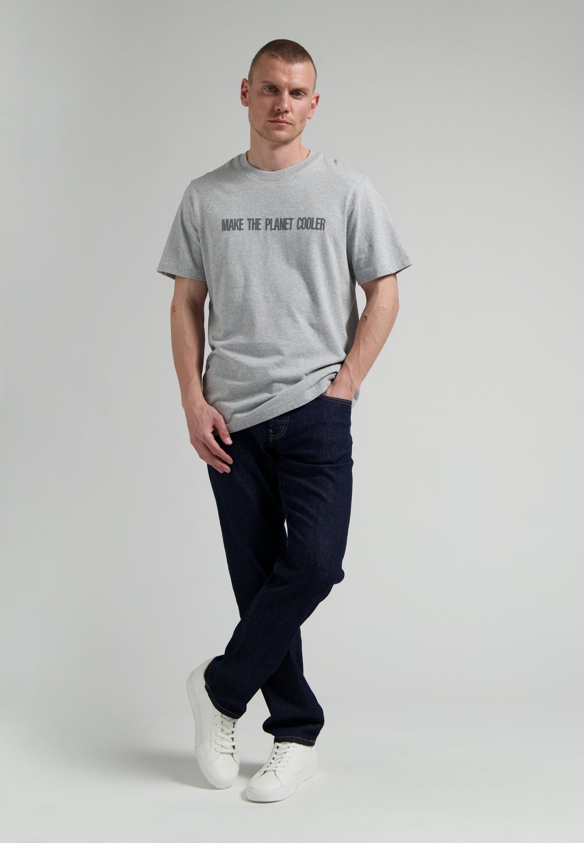 Sustainable MUD Jeans in classic blue denim, crafted from ethical materials, paired with a simple black tee and white sneakers.