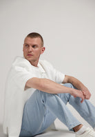 Sustainable MUD Jeans in deep blue denim, crafted ethically from organic cotton, paired with a casual white T-shirt.