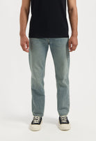 Man wearing sustainable MUD Jeans dark blue denim jacket over a tan shirt, emphasizing ethical fashion choices.