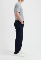 Sustainable MUD Jeans crafted from organic cotton in classic blue denim, paired with a gray t-shirt and white sneakers.