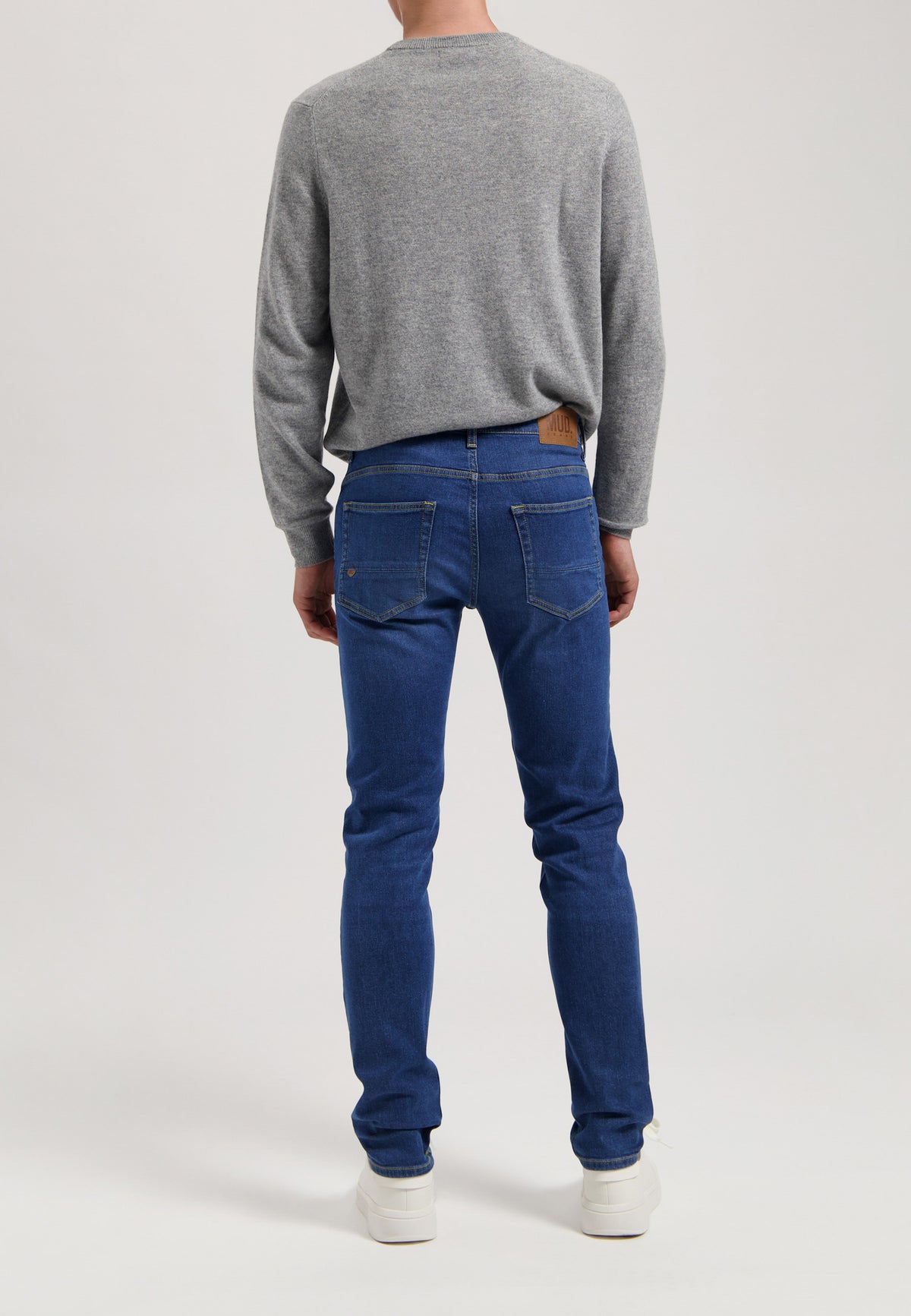Sustainable MUD Jeans denim jacket in deep blue, featuring front pockets and button closure, worn with blue denim jeans.