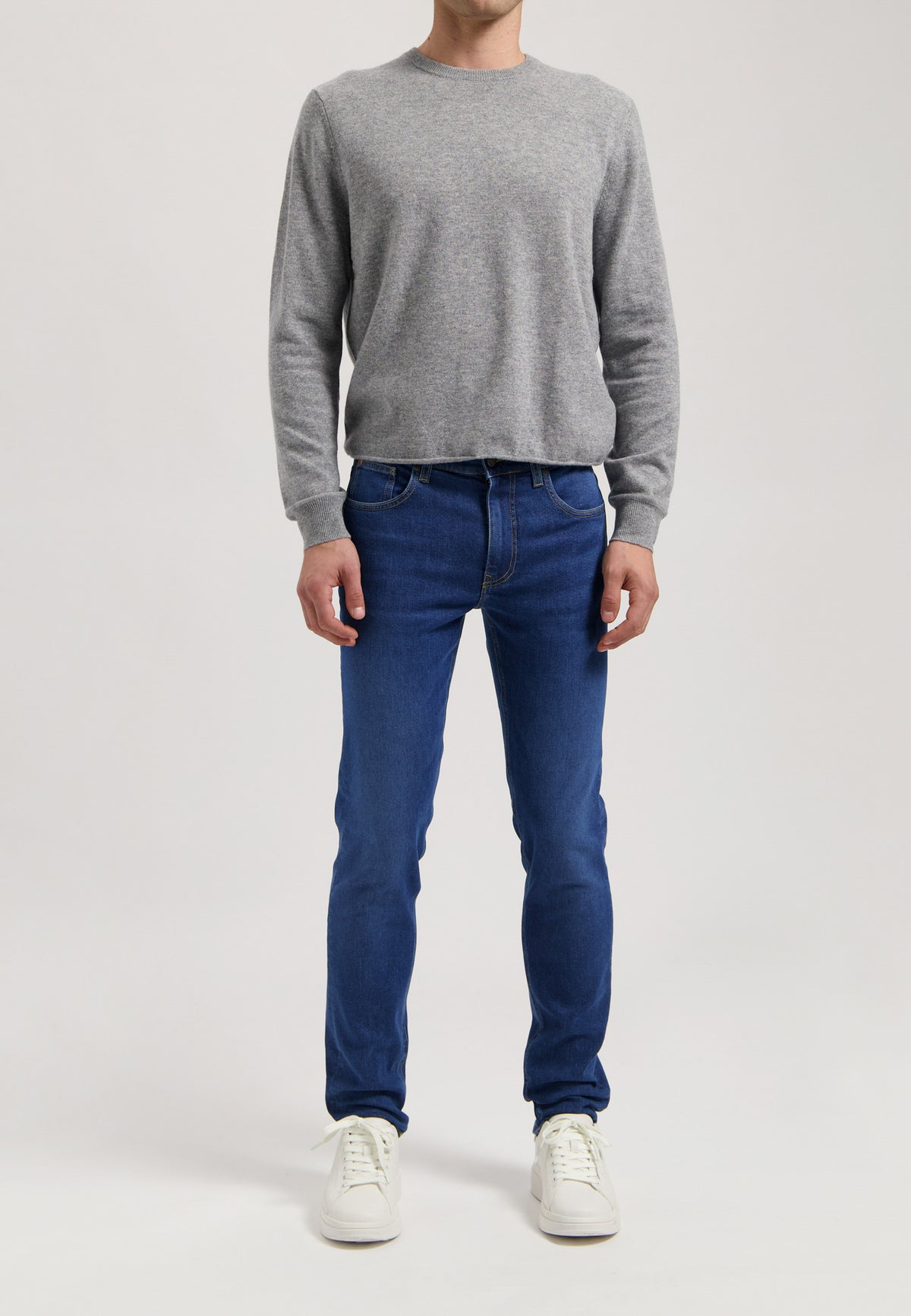 Sustainable MUD Jeans in deep blue denim, crafted ethically with organic cotton, paired with a casual gray t-shirt.