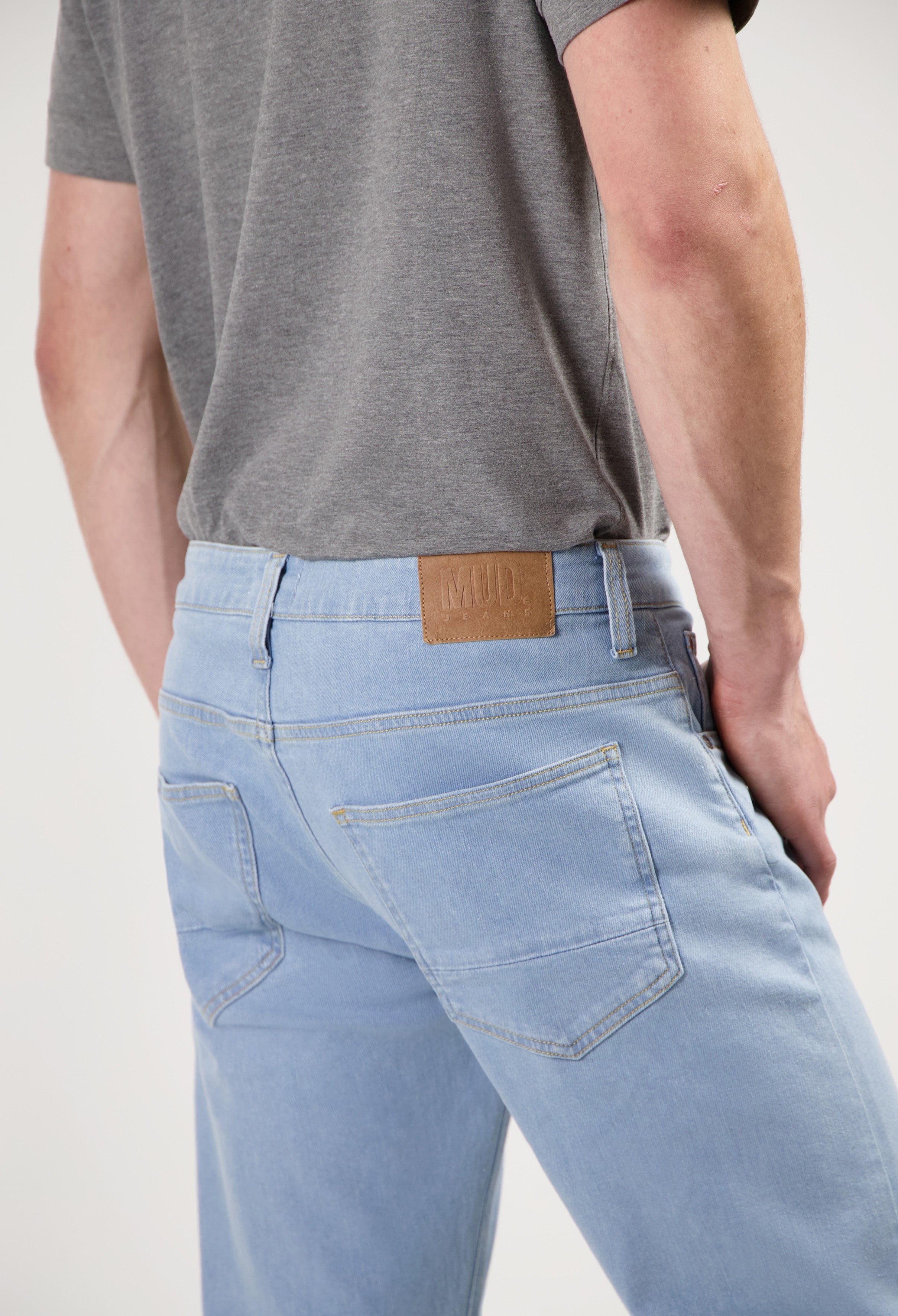 Sustainable MUD Jeans in dark gray denim, classic fit, paired with a black slogan sweatshirt and black sneakers.