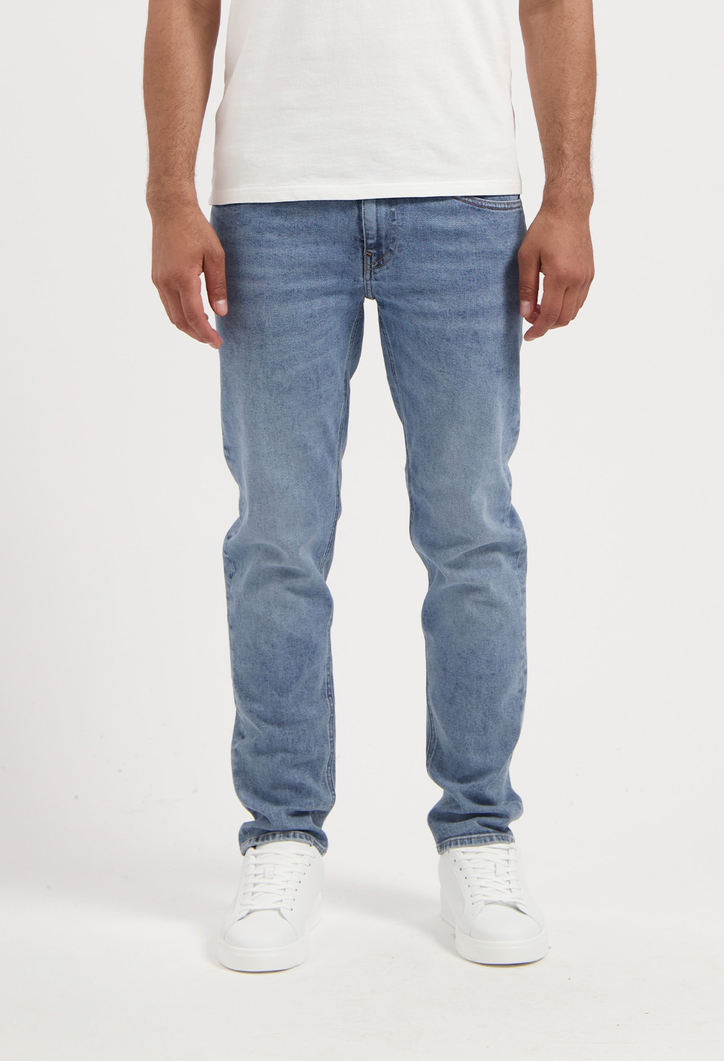 Sustainable MUD Jeans crafted shorts in blue, featuring a classic fit, worn with a black tee and white sneakers.