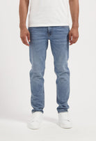 Sustainable MUD Jeans crafted shorts in blue, featuring a classic fit, worn with a black tee and white sneakers.