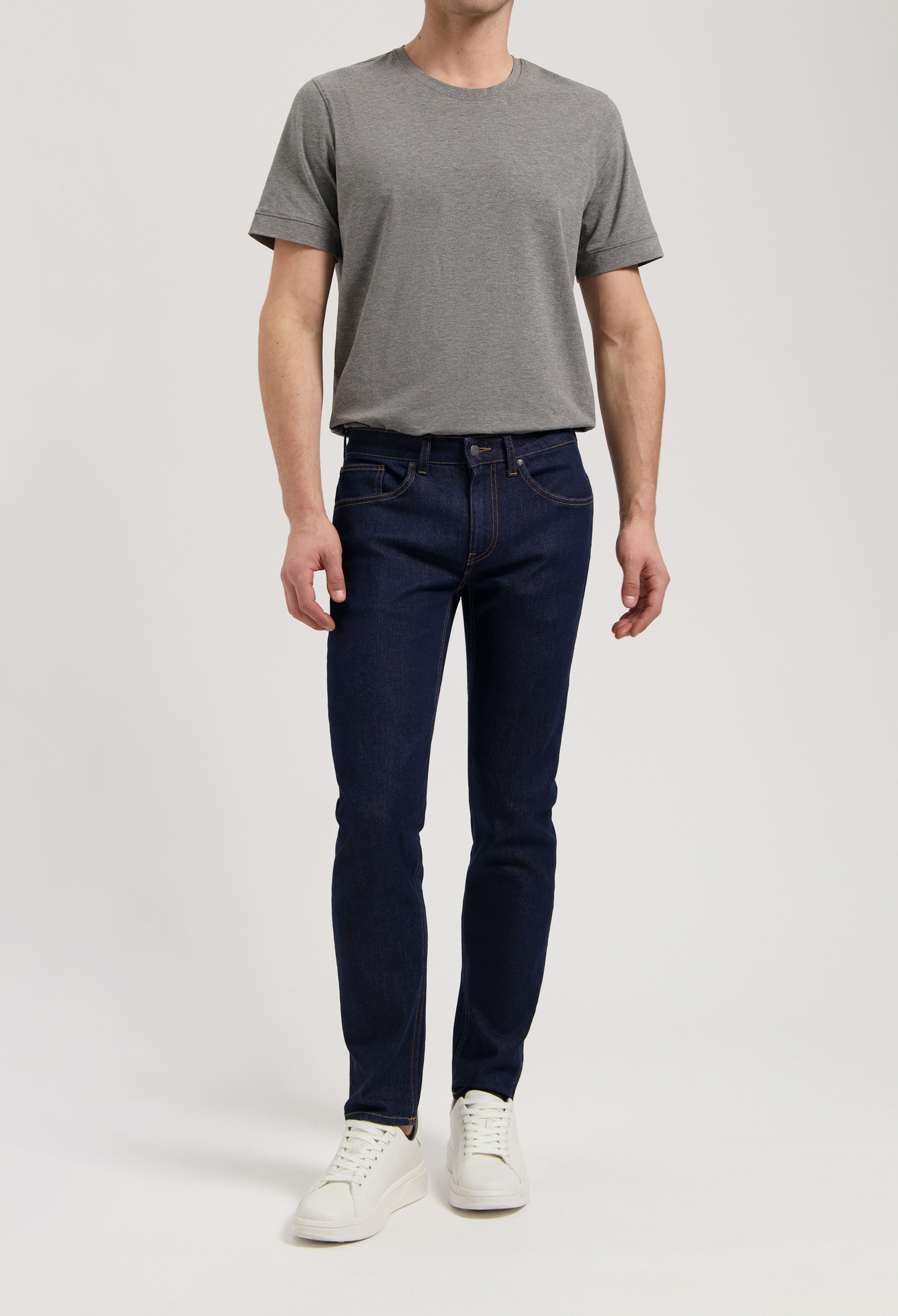 Sustainable MUD Jeans in a dark wash, crafted from organic materials, paired with a stylish gray sweater.