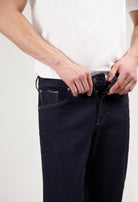 Sustainable MUD Jeans in classic blue denim, paired with a gray sweater and white sneakers for an ethical fashion look.