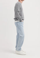 Sustainable MUD Jeans in gray denim, ethically made, paired with a black sweater and casual shoes.