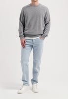 Sustainable MUD Jeans in gray denim, featuring an ethical, classic fit, paired with a black sweater and sneakers.