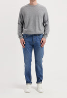 Sustainable MUD Jeans in deep blue denim, crafted from organic cotton, paired elegantly with a soft gray sweater.