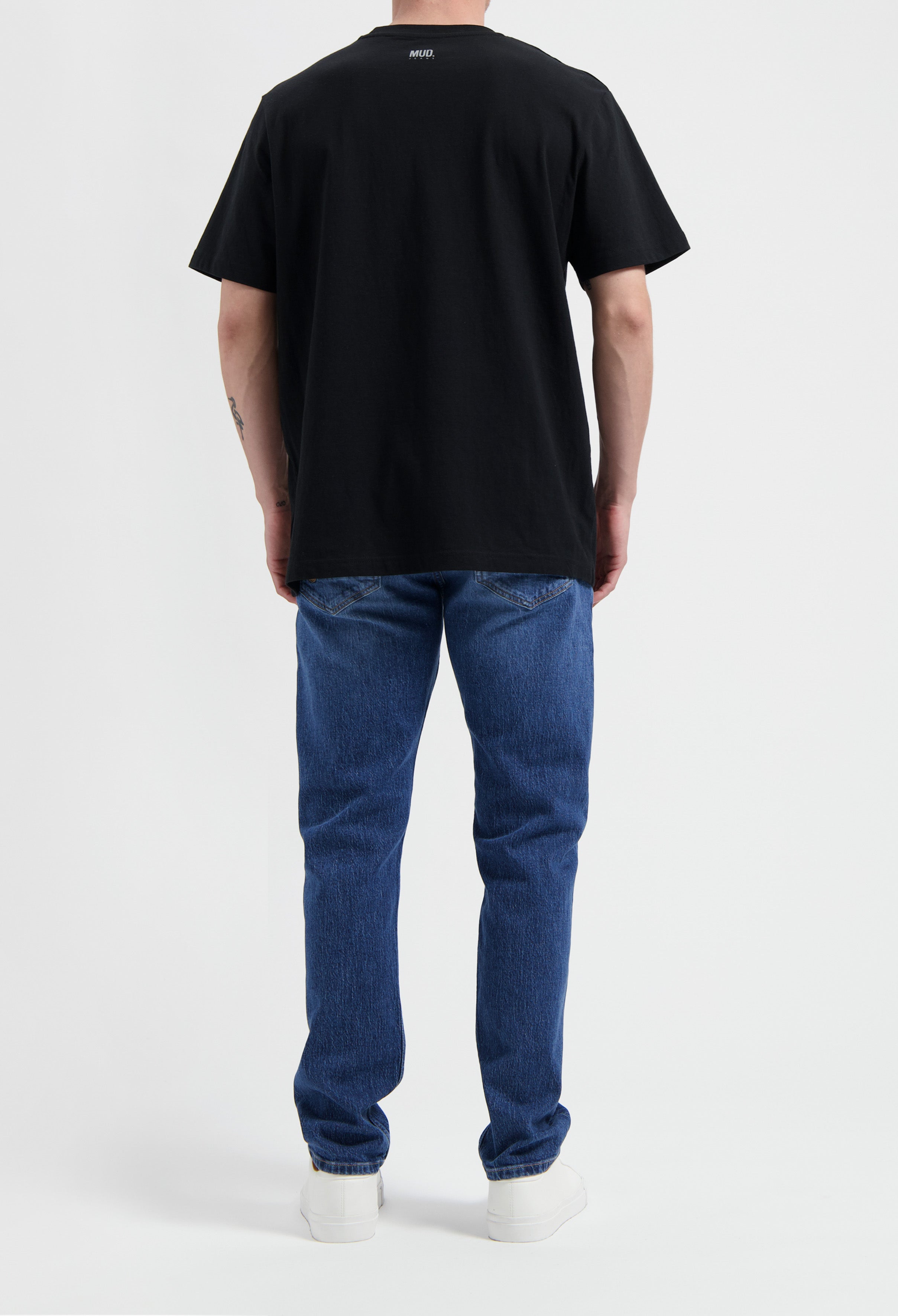 Sustainable MUD Jeans in light blue denim, crafted from organic cotton, paired with a white long-sleeve shirt.