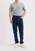 Sustainable MUD Jeans in dark denim, paired with a white T-shirt and brown sweater, showcasing ethical fashion.
