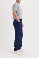 Sustainable MUD Jeans in dark denim, crafted from eco-friendly materials, paired with a white tee and brown sweater.