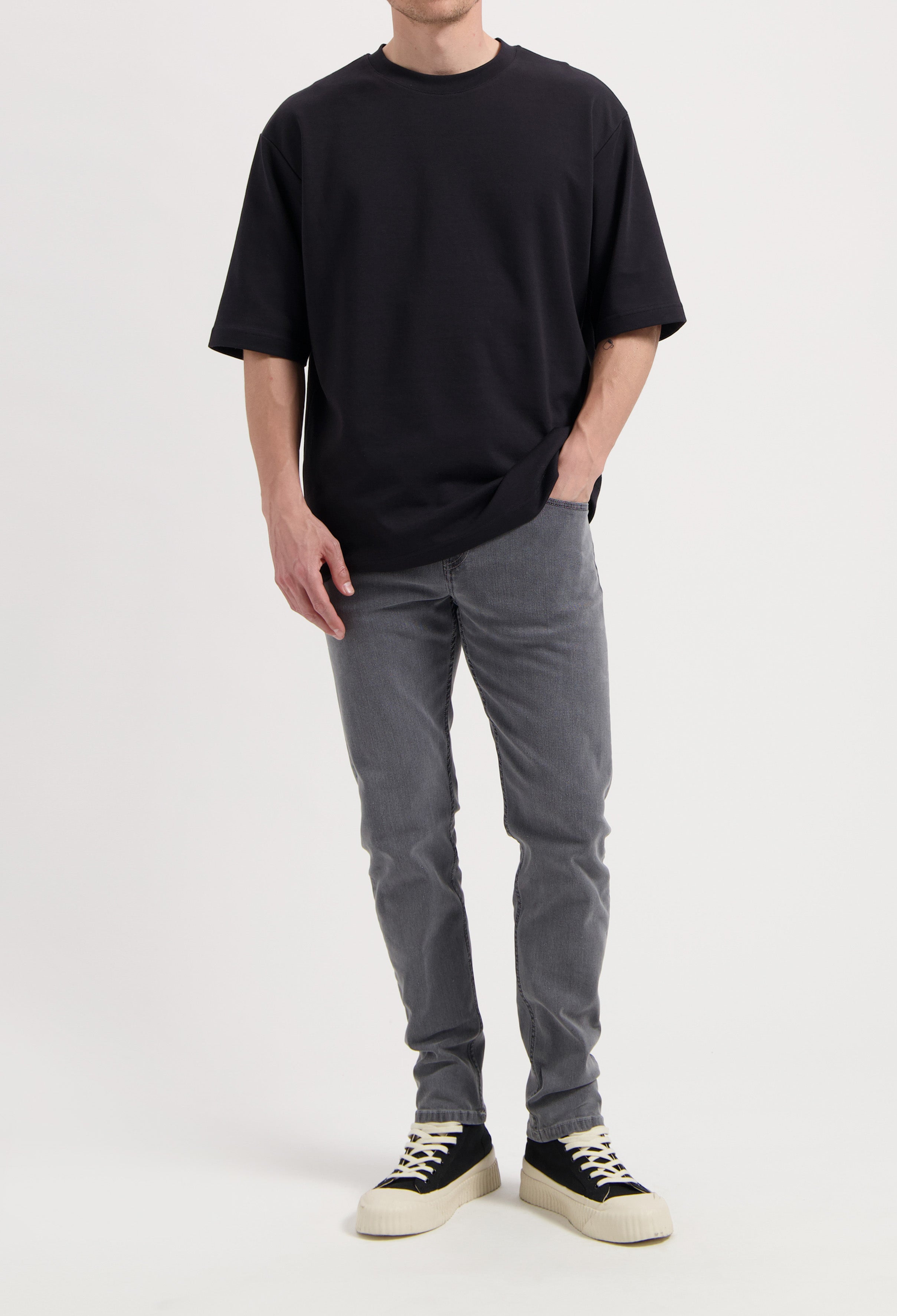 Sustainable MUD Jeans in light blue denim, ethically made from organic cotton, paired with a white long-sleeve shirt.