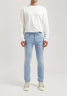 Sustainable MUD Jeans in classic blue denim, paired with a black jacket and white tee, styled for an ethical urban look.