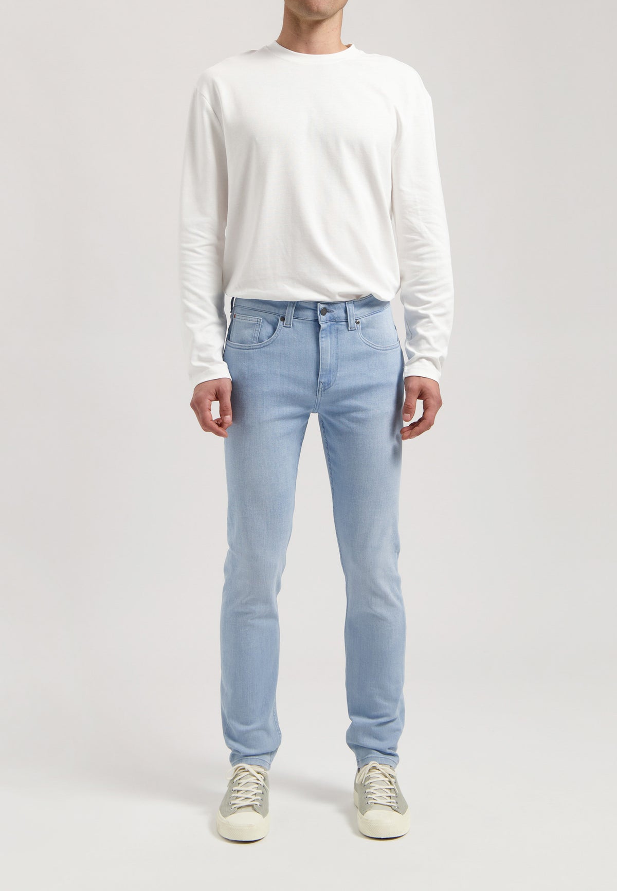 Sustainable MUD Jeans in classic blue denim, paired with a black jacket and white tee, styled for an ethical urban look.