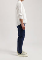 Sustainable MUD Jeans in gray denim, crafted ethically, paired with a black t-shirt and casual black sneakers.