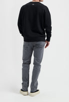 Sustainable MUD Jeans in gray denim, showcasing ethical fashion with a comfortable fit paired with a black sweatshirt.