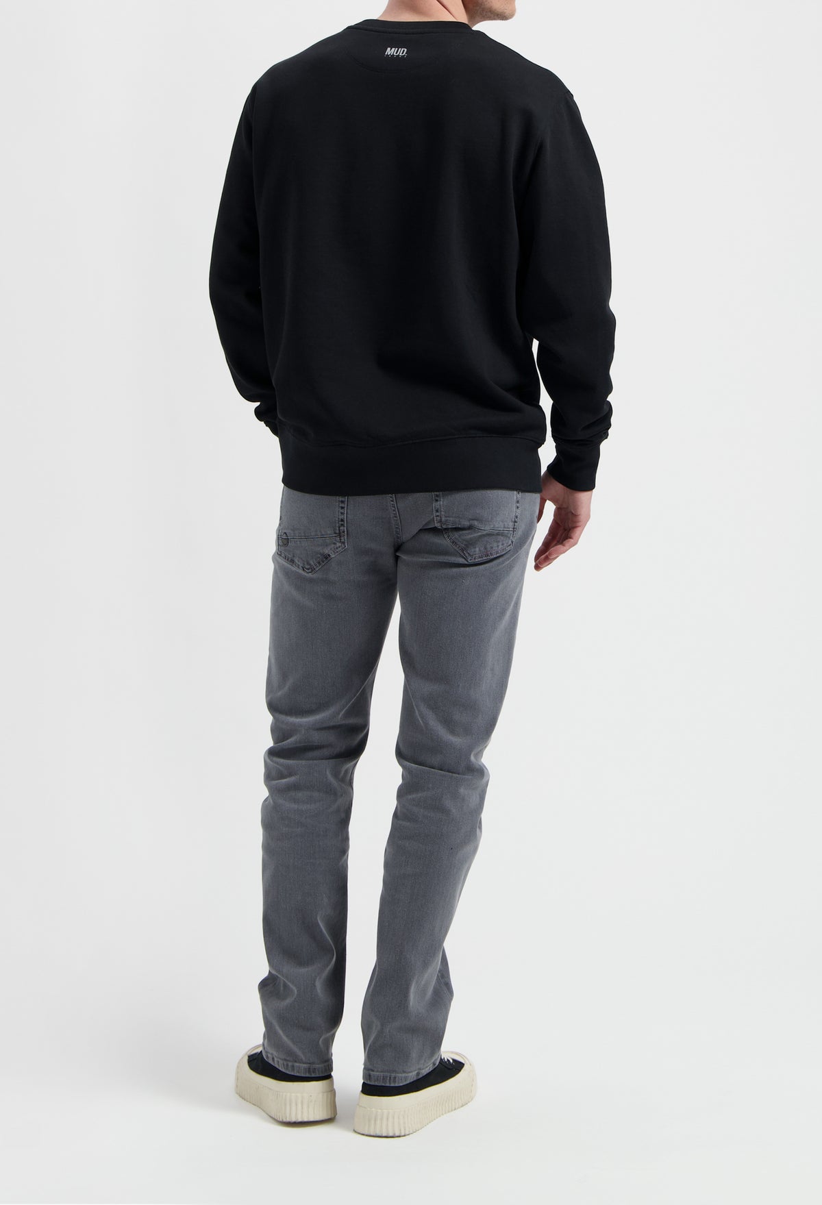 Sustainable MUD Jeans in gray denim, showcasing ethical fashion with a comfortable fit paired with a black sweatshirt.