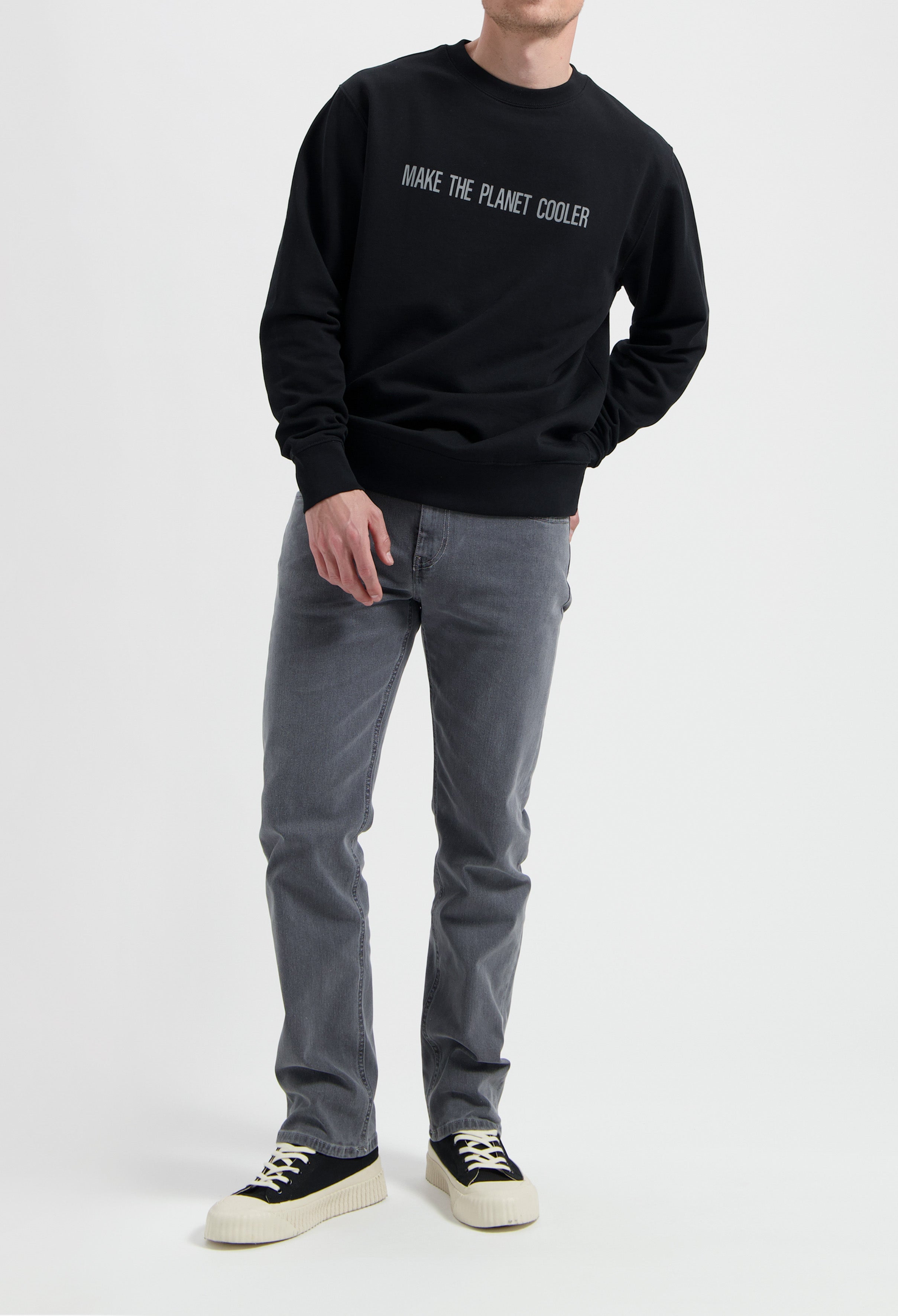Sustainable MUD Jeans in light blue denim, crafted from organic cotton, styled with white sneakers and a gray t-shirt.