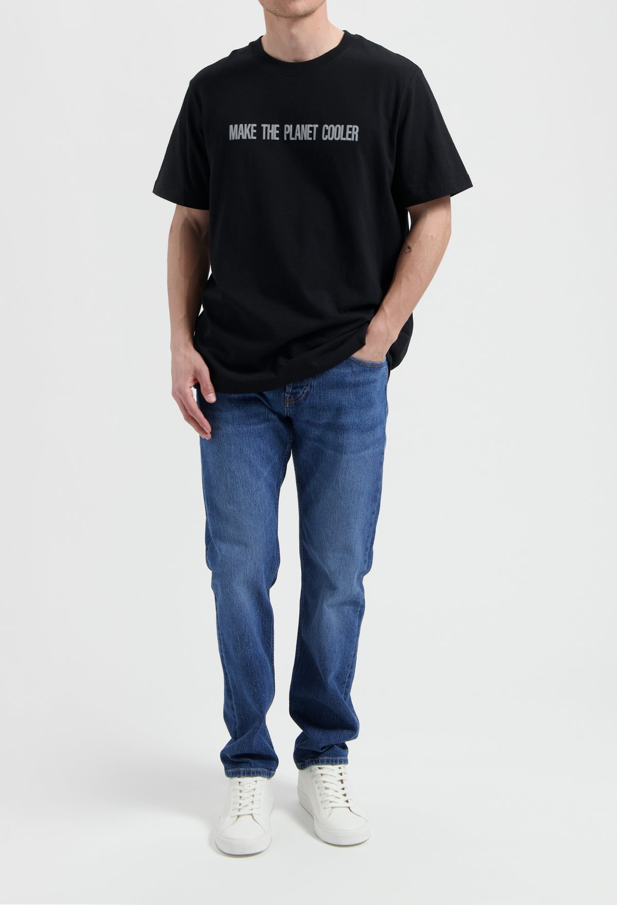 Sustainable MUD Jeans in dark brown, crafted from organic cotton, paired with a white shirt and casual sneakers.
