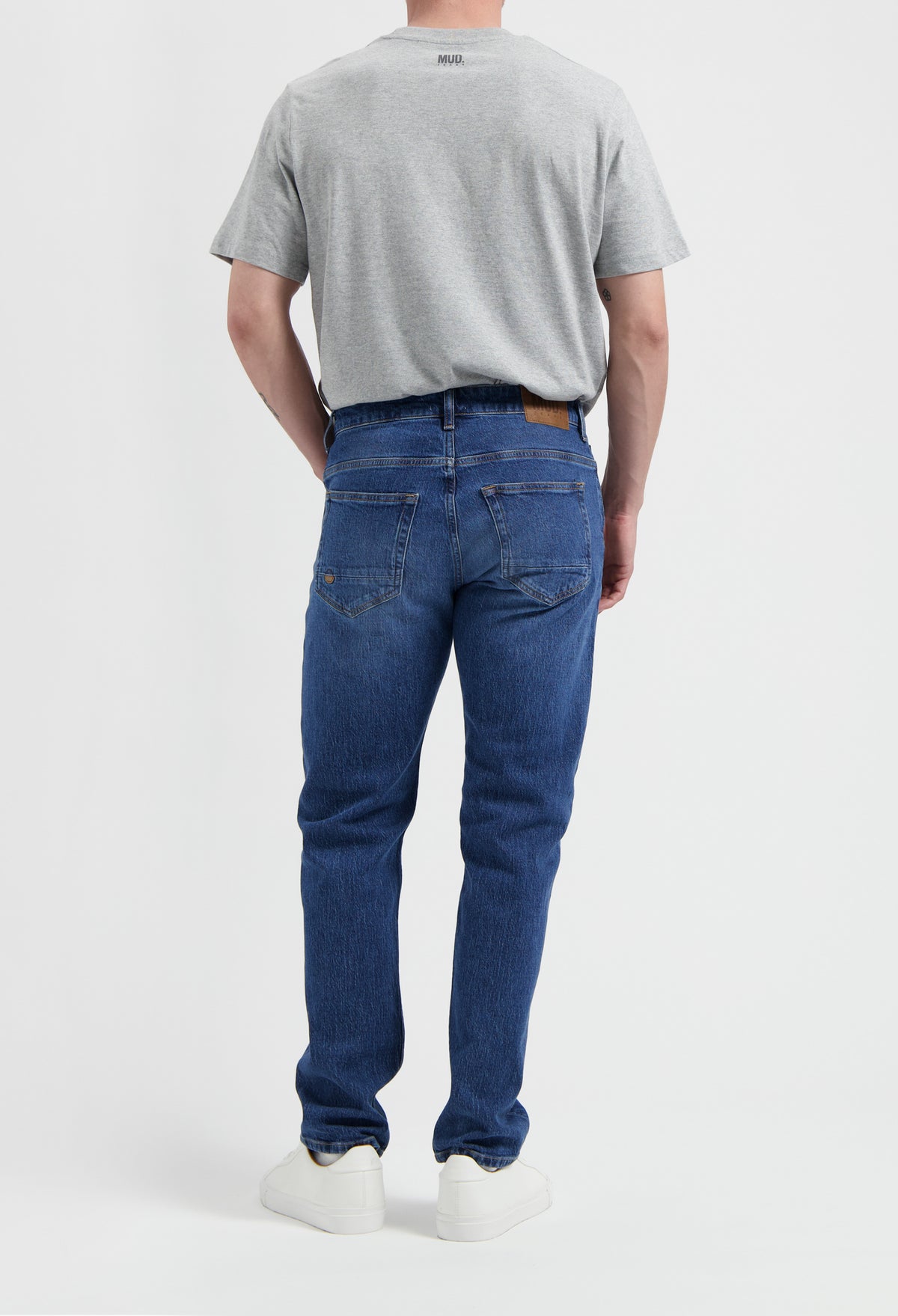 Sustainable MUD Jeans in beige, crafted from organic cotton, offering a slim fit, paired with a casual gray t-shirt.