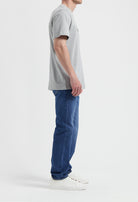 Sustainable MUD Jeans featuring beige denim, crafted ethically, paired with a casual gray t-shirt and sneakers.