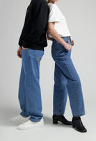 Casual blue jeans outfit with white tee and black sweatshirt, styled with white sneakers and black heeled boots.