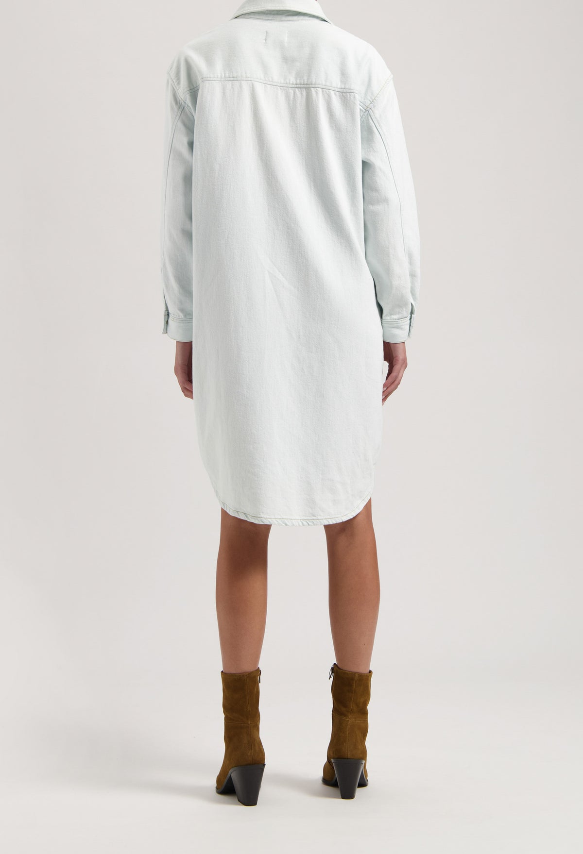 Back view of a light blue denim shirt dress paired with brown suede ankle boots, emphasizing casual style fashion.