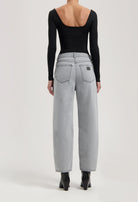 Wide-leg light gray denim jeans paired with a black long-sleeve backless top, styled with black ankle boots.