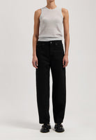 Model wearing a light gray sleeveless top and high-waisted black wide-leg jeans, paired with black shoes, against a plain background.