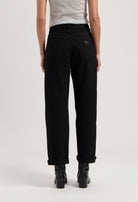 Black high-waisted jeans made of cotton, shown from the back, paired with black boots and a light gray sleeveless top.
