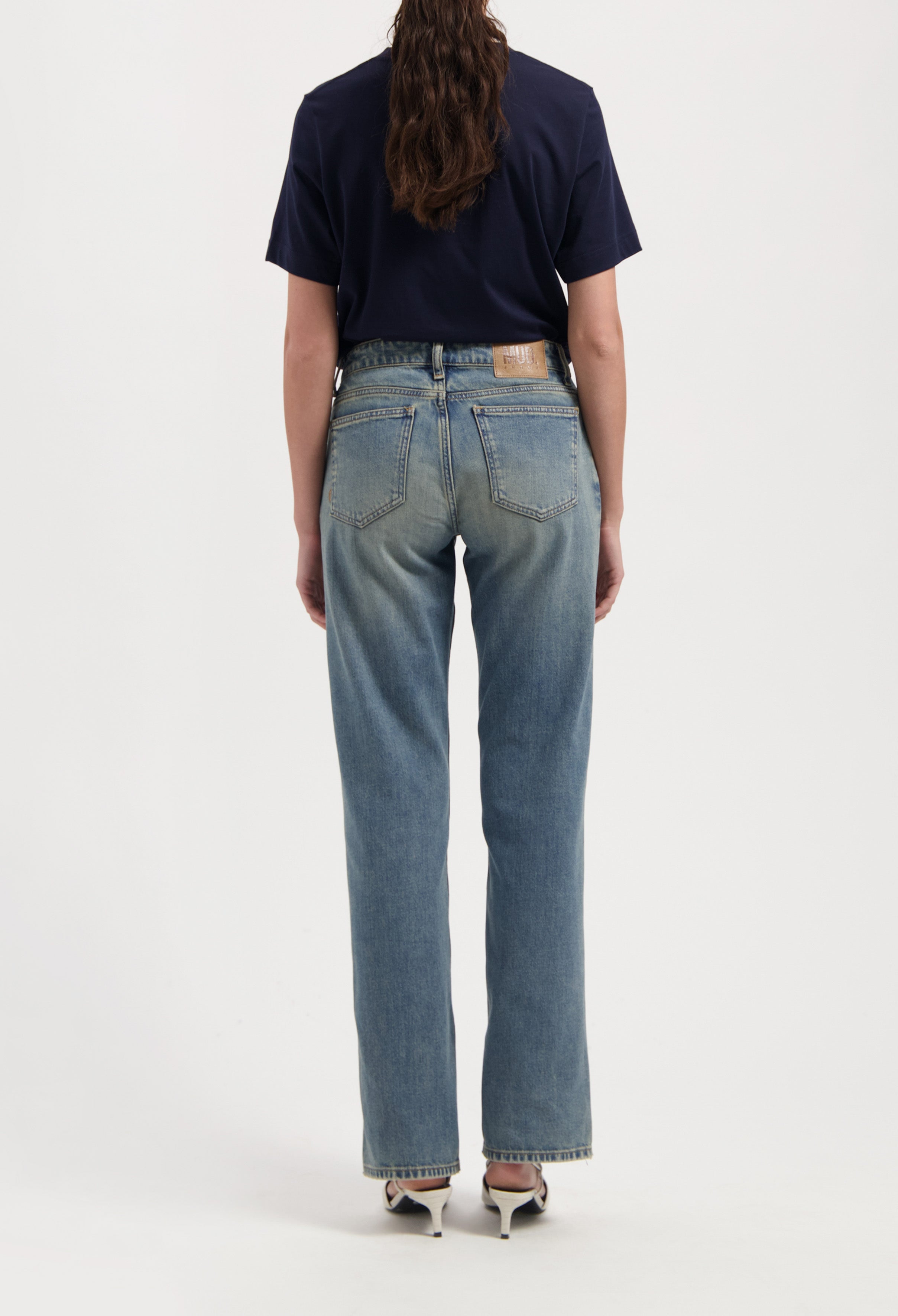 Back view of light blue straight-leg jeans with a high waist, paired with a dark navy short-sleeve T-shirt, worn by a woman.