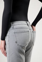 Person wearing light gray jeans with back pockets, styled with a black long-sleeve top, showcasing casual fashion.