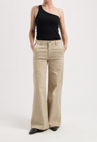 Wide-leg beige trousers paired with an asymmetrical black top, showcasing a minimalistic and stylish outfit.