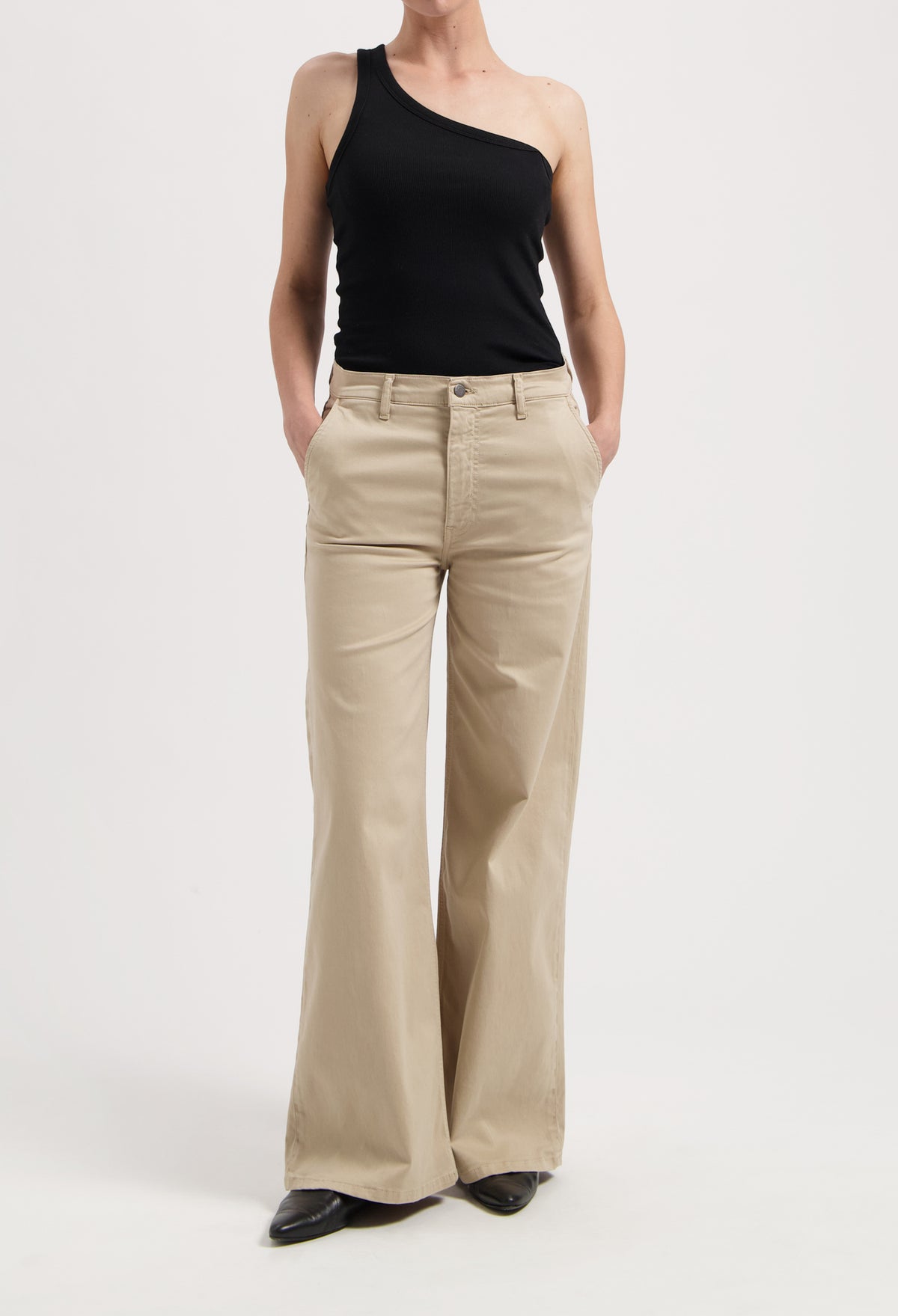 Wide-leg beige trousers paired with an asymmetrical black top, showcasing a minimalistic and stylish outfit.