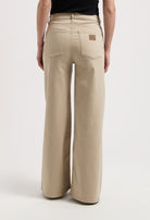 Wide-leg stone-colored MUD Jeans made from organic cotton, showcasing high-waisted fit and detailed back pockets.