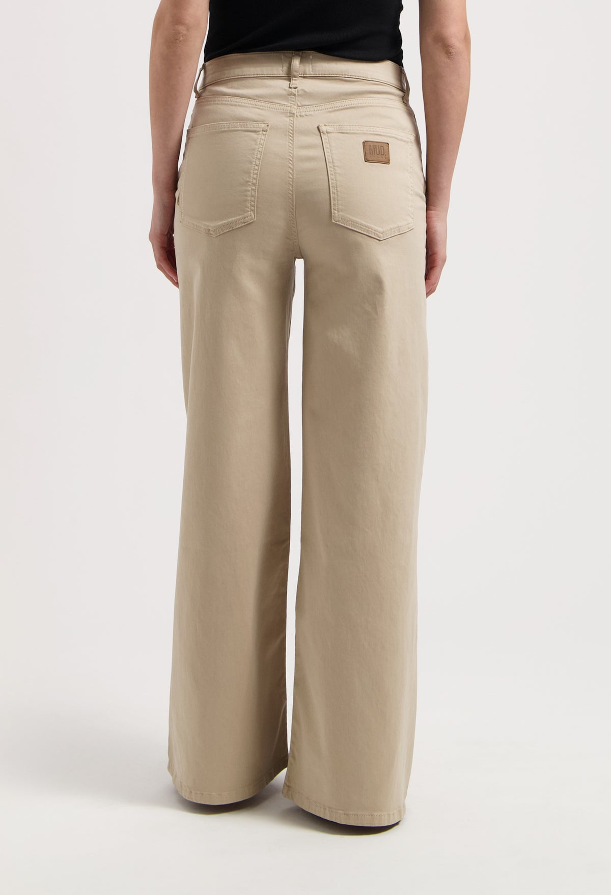 Wide-leg stone-colored MUD Jeans made from organic cotton, showcasing high-waisted fit and detailed back pockets.