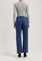 Light gray long-sleeve top paired with relaxed-fit MUD Jeans in classic blue denim, viewed from the back.