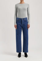 Gray long-sleeve top paired with classic high-waisted blue denim jeans, showcasing casual chic fashion style.
