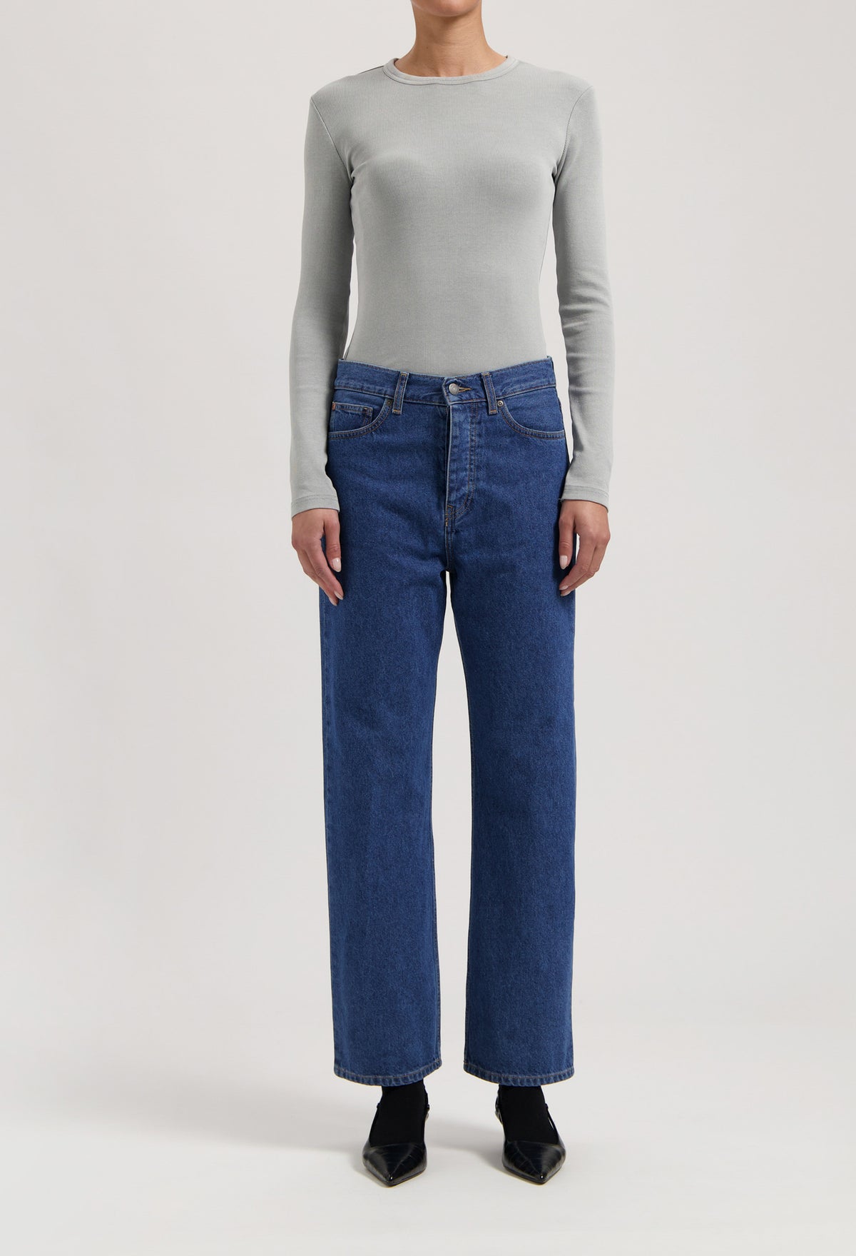 Gray long-sleeve top paired with classic high-waisted blue denim jeans, showcasing casual chic fashion style.