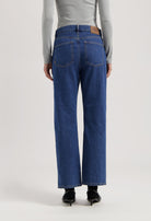 Back view of sustainable MUD Jeans, organic blue denim, wide-leg fit, paired with a light gray long-sleeve top.