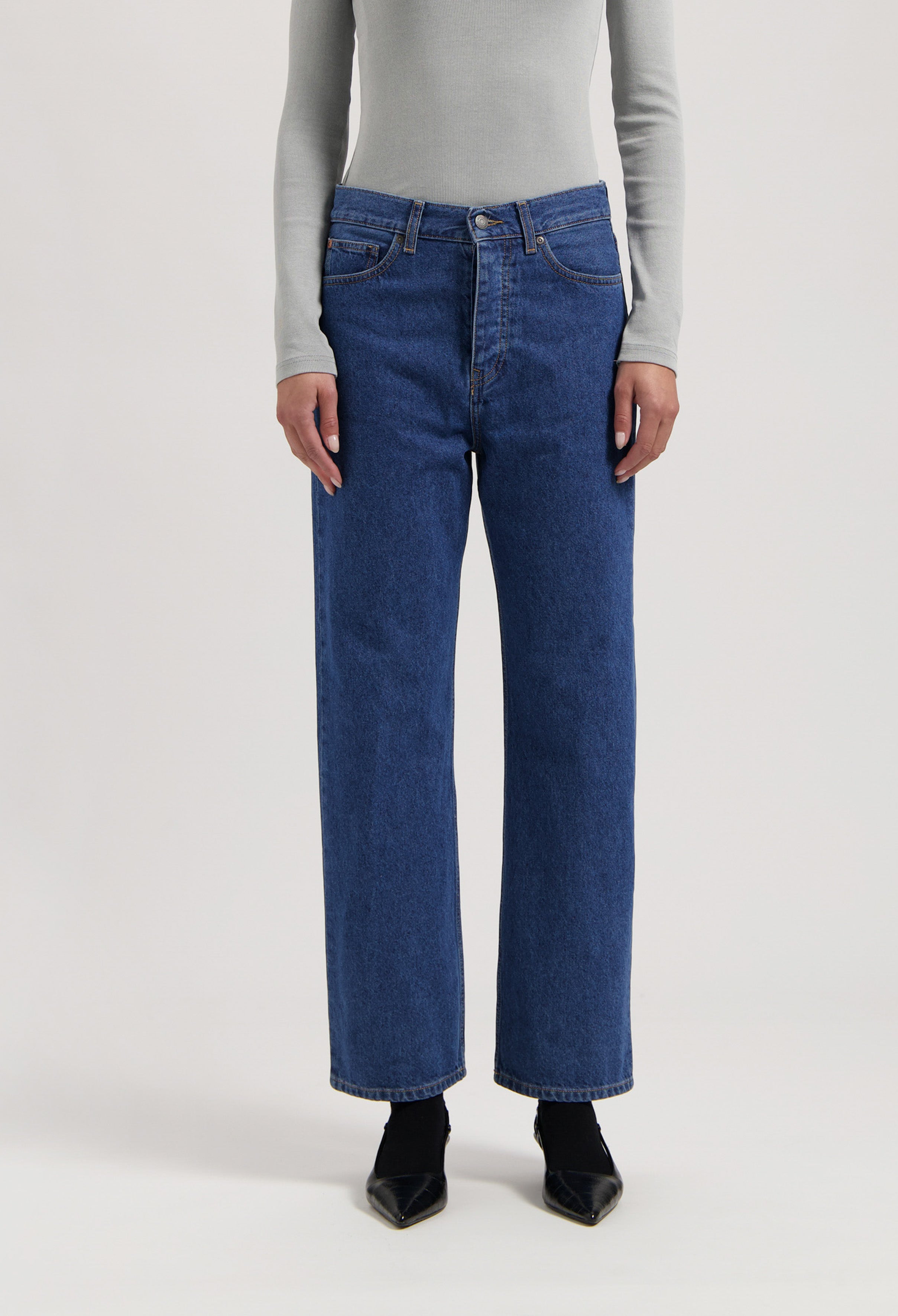 Wide-leg denim jeans in classic blue, paired with a light gray long-sleeve top, highlighting a simple, chic outfit.