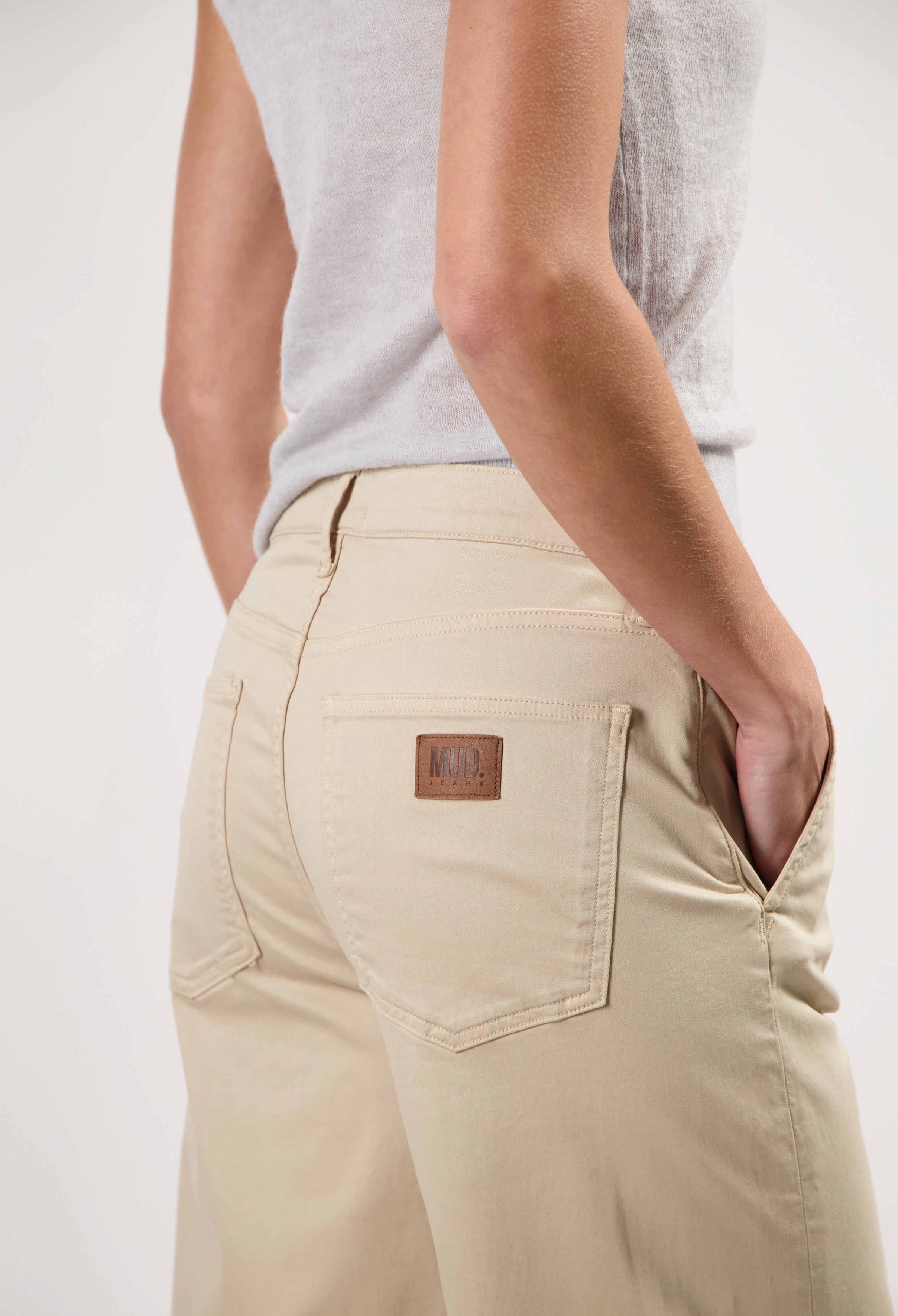 Beige MUD Jeans crafted from sustainable materials, showcasing a rear view of the relaxed-fit, casual trousers with logo detail.