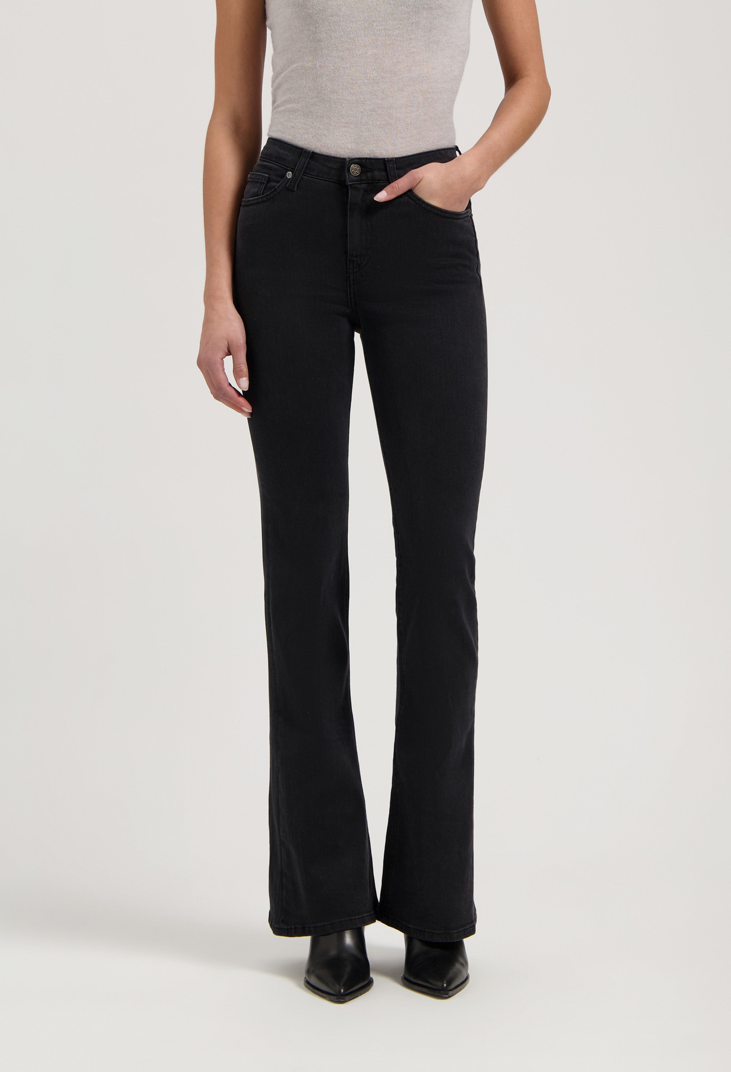 Black flared jeans in a soft, stretchy fabric, paired with a light gray sleeveless top and black pointed-toe boots.